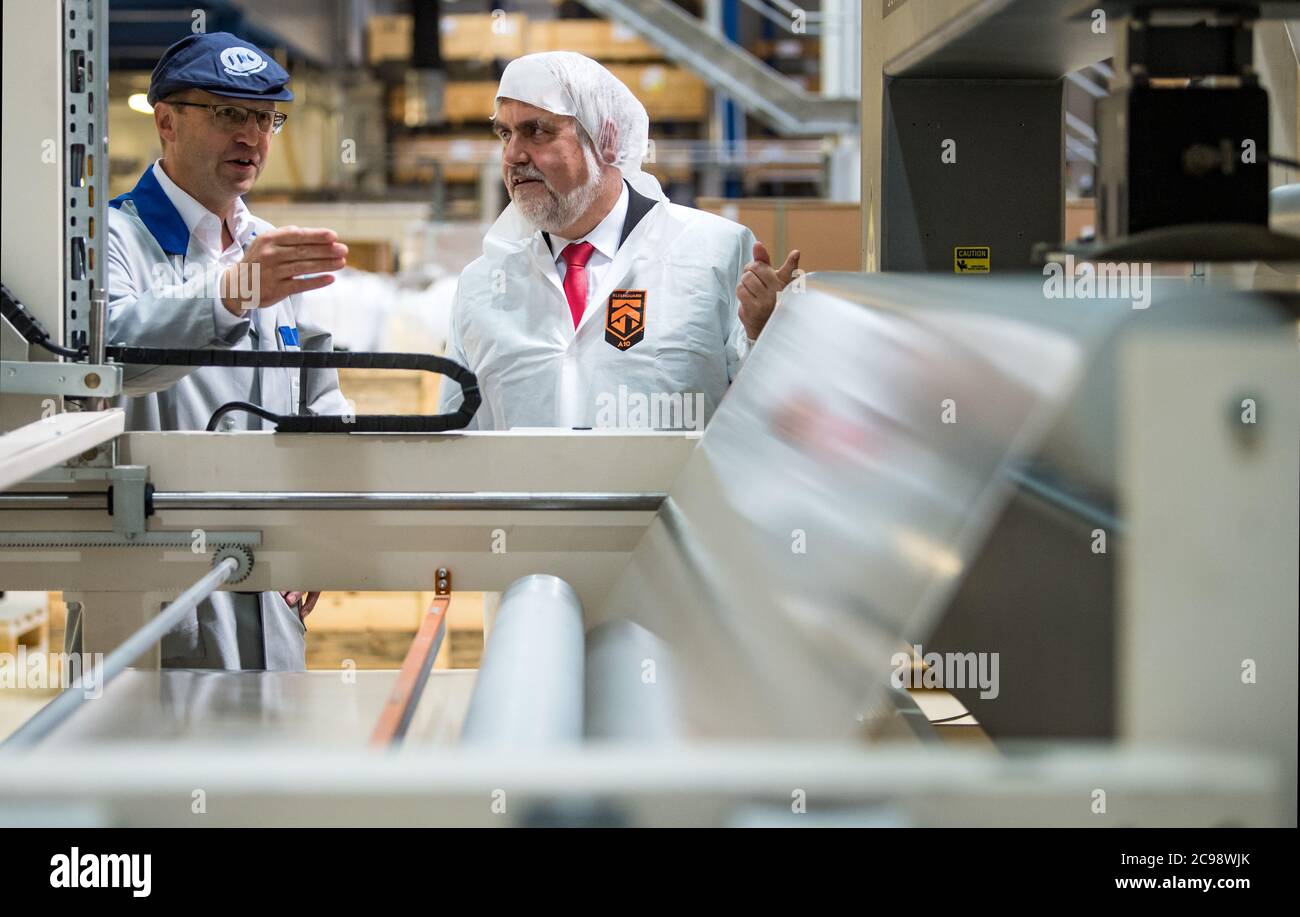29. Juli 2020, Sachsen-Anhalt, Bitterfeld-Wolfen: Thomas Olszowy (l.), Prokurist des Folienwerks Wolfen, und Armin Willingmann (SPD), Wirtschaftsminister von Sachsen-Anhalt, sprechen auf einer Extrusionsanlage zur Herstellung von EVA-Folien für Sicherheitsglas. Das Folienwerk Wolfen beschäftigt 140 Mitarbeiter und produziert Folien auf derzeit sieben Extrusionsanlagen mit einer maximalen Kapazität von 20,000 Tonnen. Das Unternehmen erwirtschaftet einen Umsatz von rund 35 Millionen Euro, rund 70 Prozent der Produktion werden exportiert. Im Rahmen der Sommertournee des Ministers vergibt das Wirtschaftsministerium Sachsen-Anhalt Preise an 'fut Stockfoto