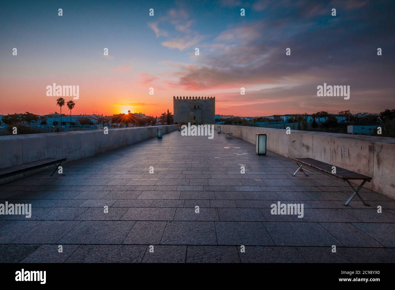 Sonnenaufgang in der spanischen Stadt Cordoba mit dramatischen Morgenwolken. Historische römische Brücke in der Altstadt. Brückenturm mit Fußweg über den Fluss Stockfoto