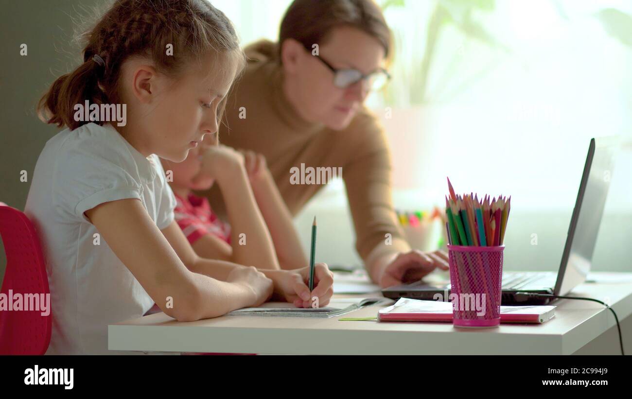 Nette Kinder verwenden Laptop für Bildung, Online-Studie, zu Hause studieren, Junge und Mädchen haben Hausaufgaben auf Distanz lernen. Lifestyle-Konzept für Home Schooling. Mutter hilft Tochter und Sohn. Stockfoto