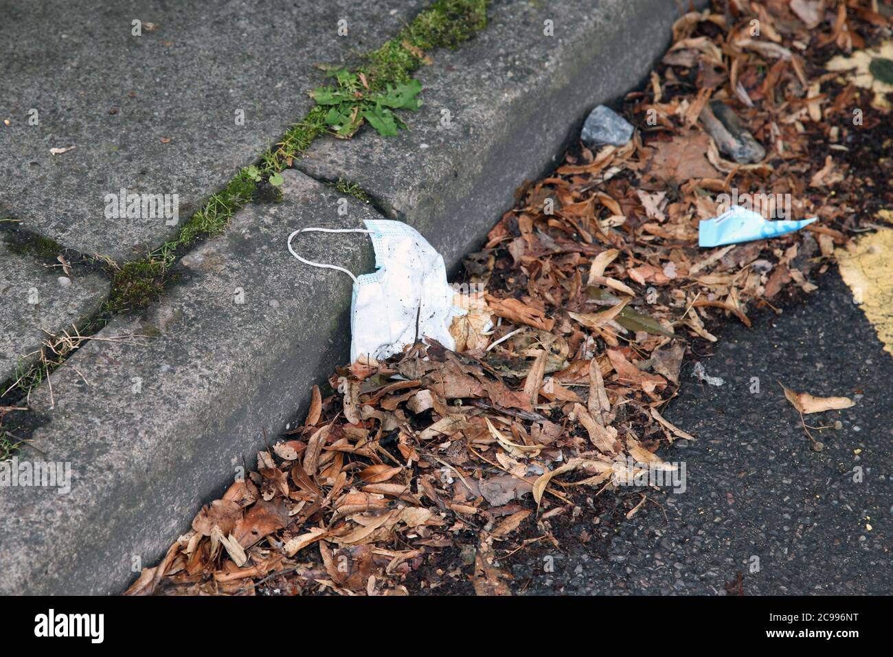 Eine Einweg-Gesichtsmask liegt auf der Straße weggeworfen Müll an der Bordwand, Großbritannien, Juli 2020 Stockfoto