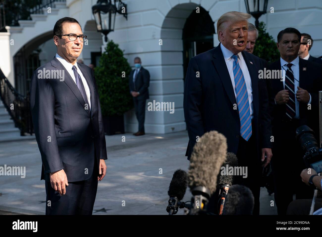 US-Finanzminister Steven Mnuchin hört zu, wie US-Präsident Donald J. Trump vor dem Weißen Haus in Washington, DC, USA, am Mittwoch, den 29. Juli 2020, vor der Presse spricht. Quelle: Sarah Silbiger/Pool via CNP /MediaPunch Stockfoto