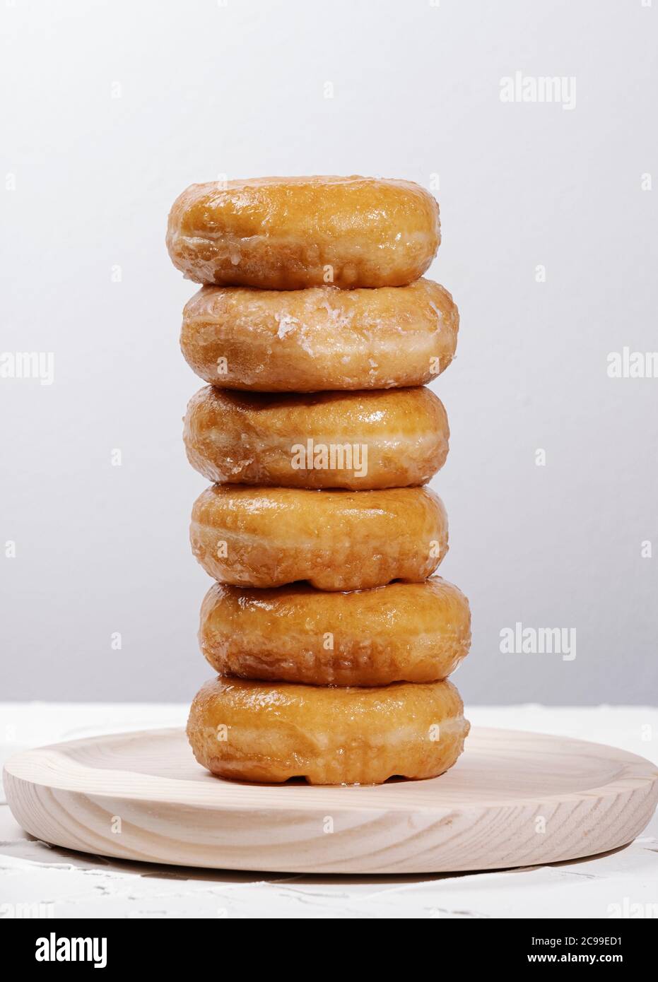 Berg von Donuts auf einem runden Holztisch auf weißem Hintergrund Stockfoto