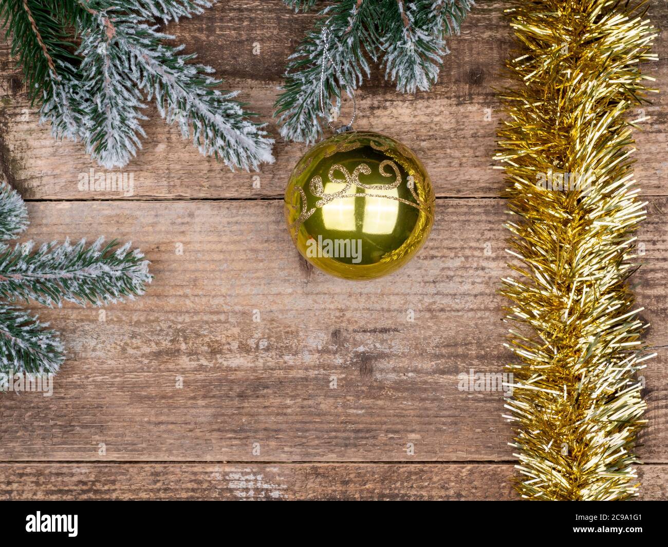 Schneebedeckte Zweige eines Weihnachtsbaums, eine gelbe Kugel und Regen. Stockfoto