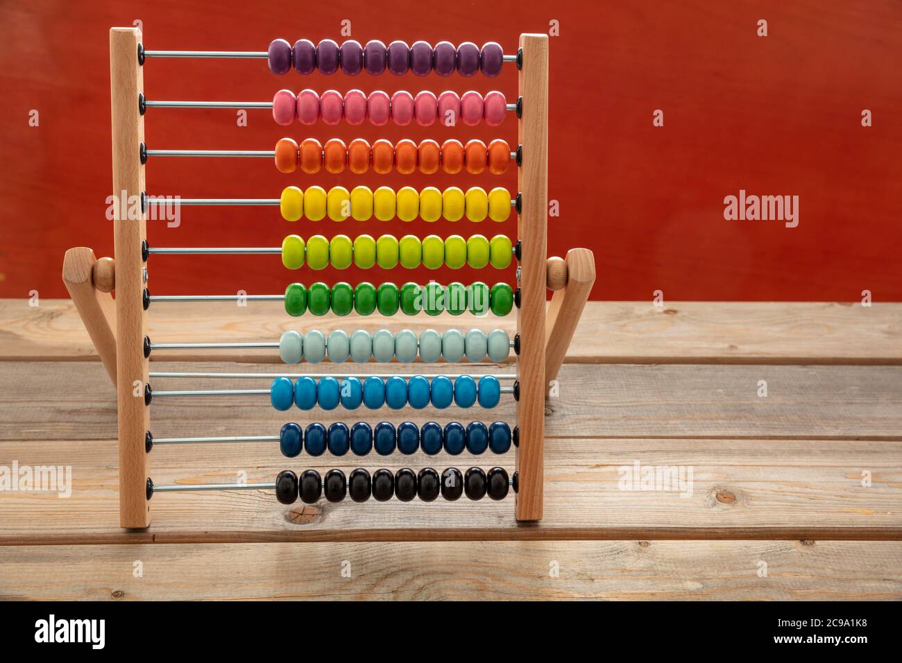 Schule Abacus mit bunten Perlen stehen auf Holzschreibtisch, rote Farbe Wand Hintergrund, Kopie Raum. Kinder lernen zählen, Kinder Mathe Klasse Konzept Stockfoto