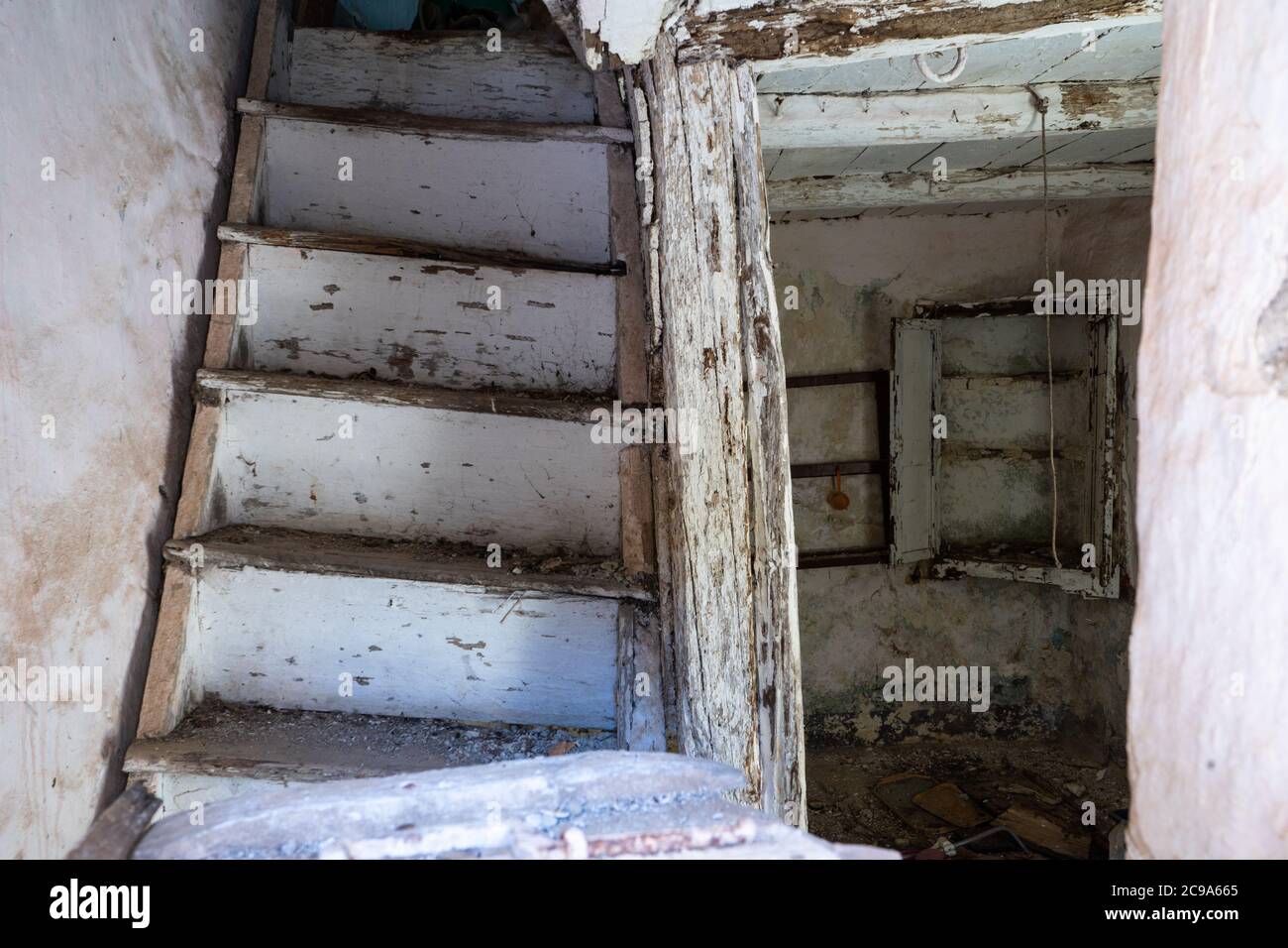 Ein bröckelndes Haus in Lamezia Terme, Italien. Bild durch das Fenster eines Treppenhauses und Blick auf das Erdgeschoss. Stockfoto