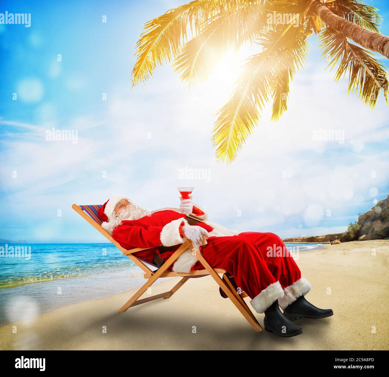 Weihnachtsmann entspannt auf einem Liegestuhl an einem tropischen Strand Stockfoto