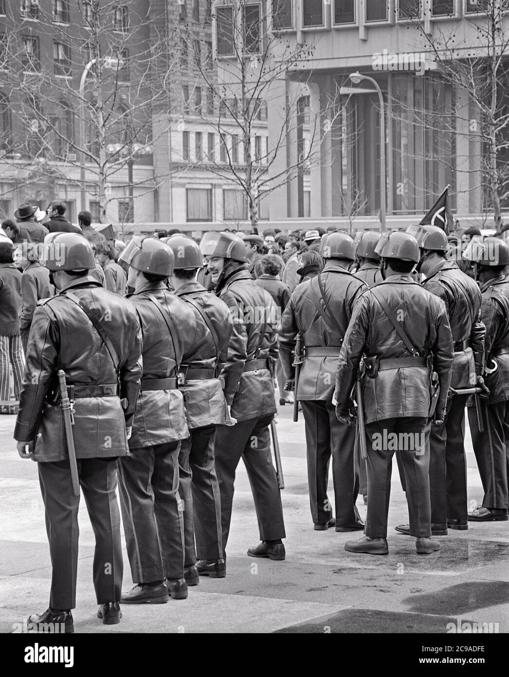 1960S 70S LINIE VON POLIZISTEN IN BEREITSCHAFTAUSRÜSTUNG BEI PROTESTKUNDGEBUNG DEMONSTRATION PHILADELPHIA PA USA - P7730 HAR001 HARS MASSE PERSONEN MÄNNER RISIKO AUFTRAG OFFICER ZUSCHAUER B&W SAMMELN TRAURIGKEIT COP FREIHEIT SCHUTZ STÄRKE STRATEGIE MUT UND AUFREGUNG AUSSEN PA MÄCHTIG BEI IN DER AUTORITÄT DEMONSTRATION BERUFE POLITIK UNIFORMEN KONZEPTIONELLE HELMETS OFFIZIERE POLIZISTEN POLIZISTEN IDEEN RALLYE GEDRÄNGE ZWEISAMKEIT ANWESENHEITSABZEICHEN SCHWARZ UND WEISS HAR001 ALTMODISCH Stockfoto