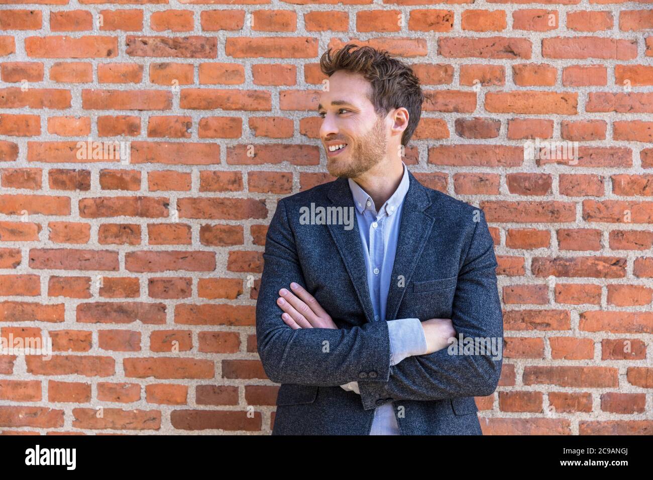 Zuversichtlich Unternehmer Mann junge Geschäftsmann Blick auf die Seite Porträt gegen Stadtbüro Backstein Wand Hintergrund. Lächelnder kaukasischer Rüde Stockfoto