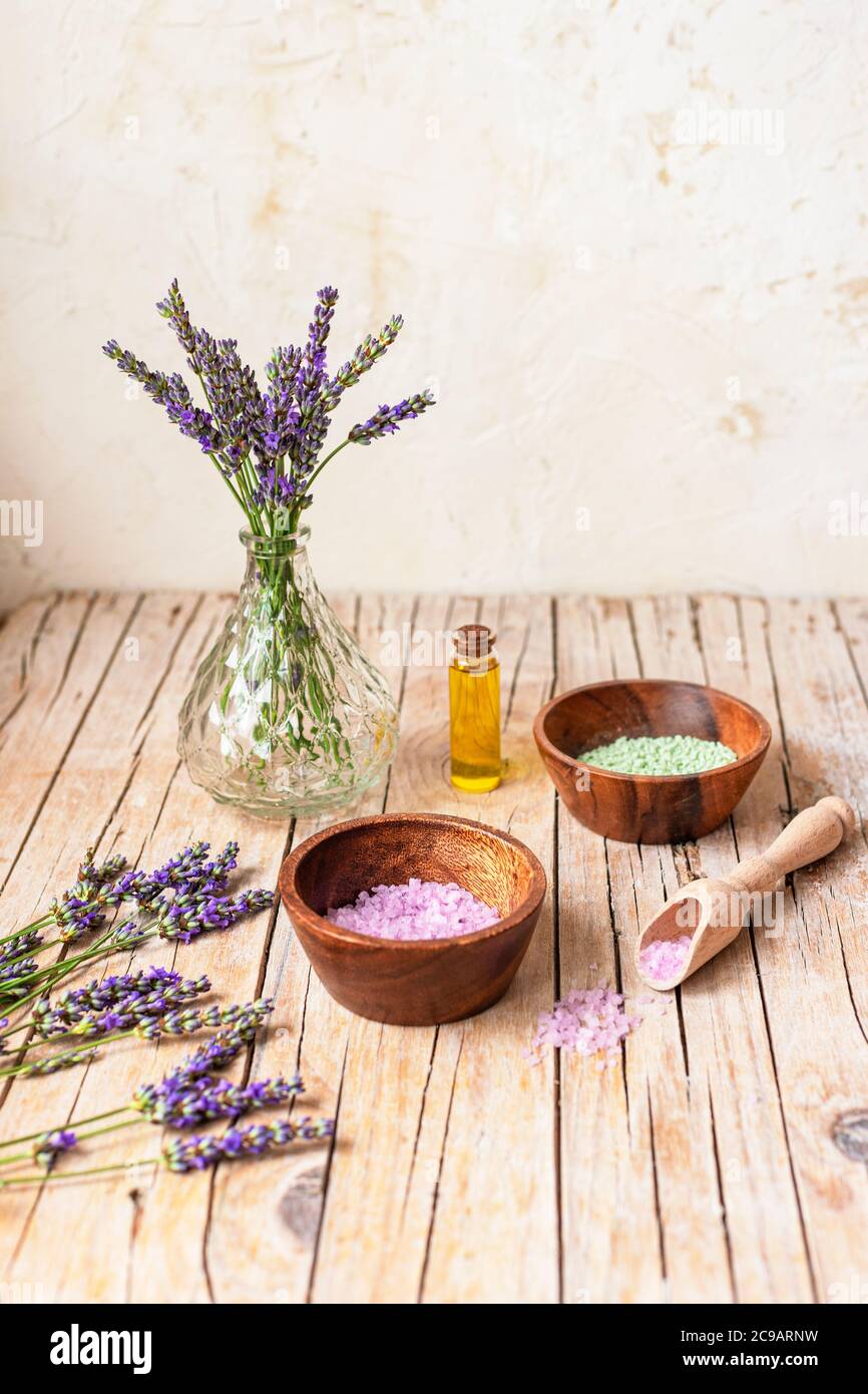 Flasche ätherisches Öl und Schalen mit Meersalz auf Holztisch. Lavendel Kosmetik, Spa und Wellness-Konzept. Selektiver Fokus. Stockfoto