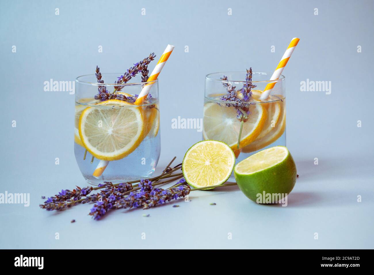 Gläser mit Lavendellimonade auf hellgrauem Hintergrund, Blumen und Limettenscheiben. Nahaufnahme, Vorderansicht Stockfoto