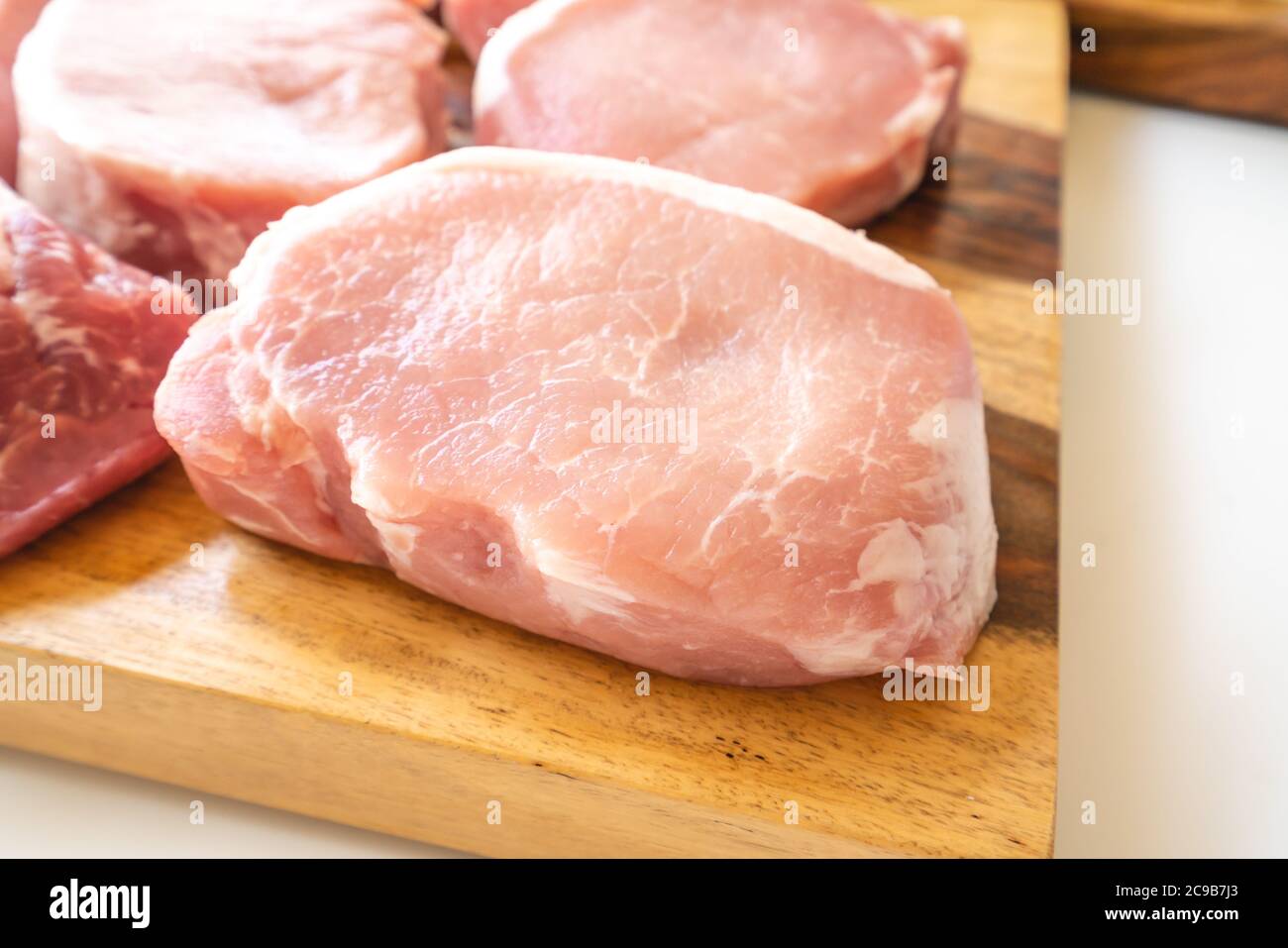 Knochenlose rohe Schweinelende Koteletts aus nächster Nähe auf Holzschneidebrett Stockfoto