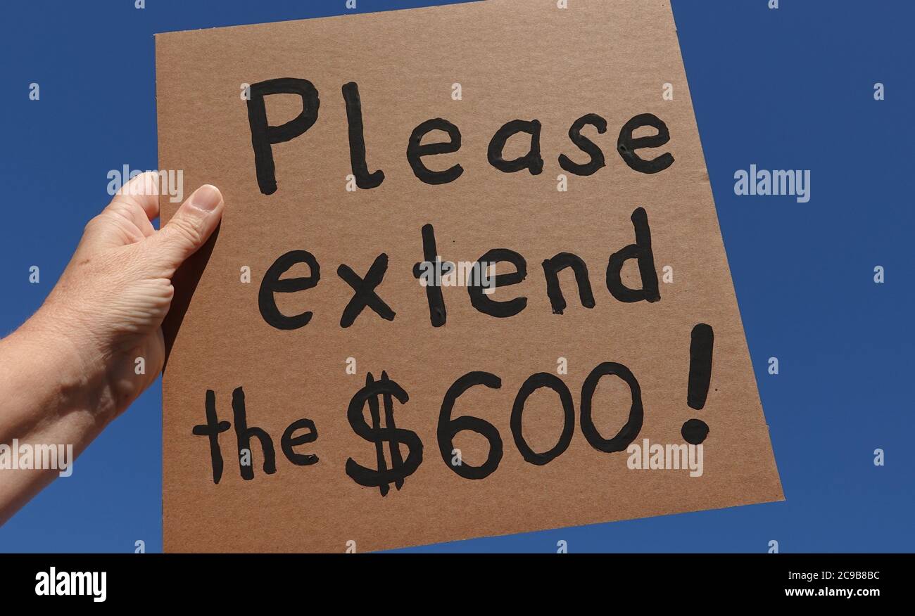 Eine Hand einer Frau mit einem handgefertigten Pappschild, die die US-Regierung bittet, die verlängerten Arbeitslosengeld-Leistungen von 600 Dollar fortzusetzen Stockfoto