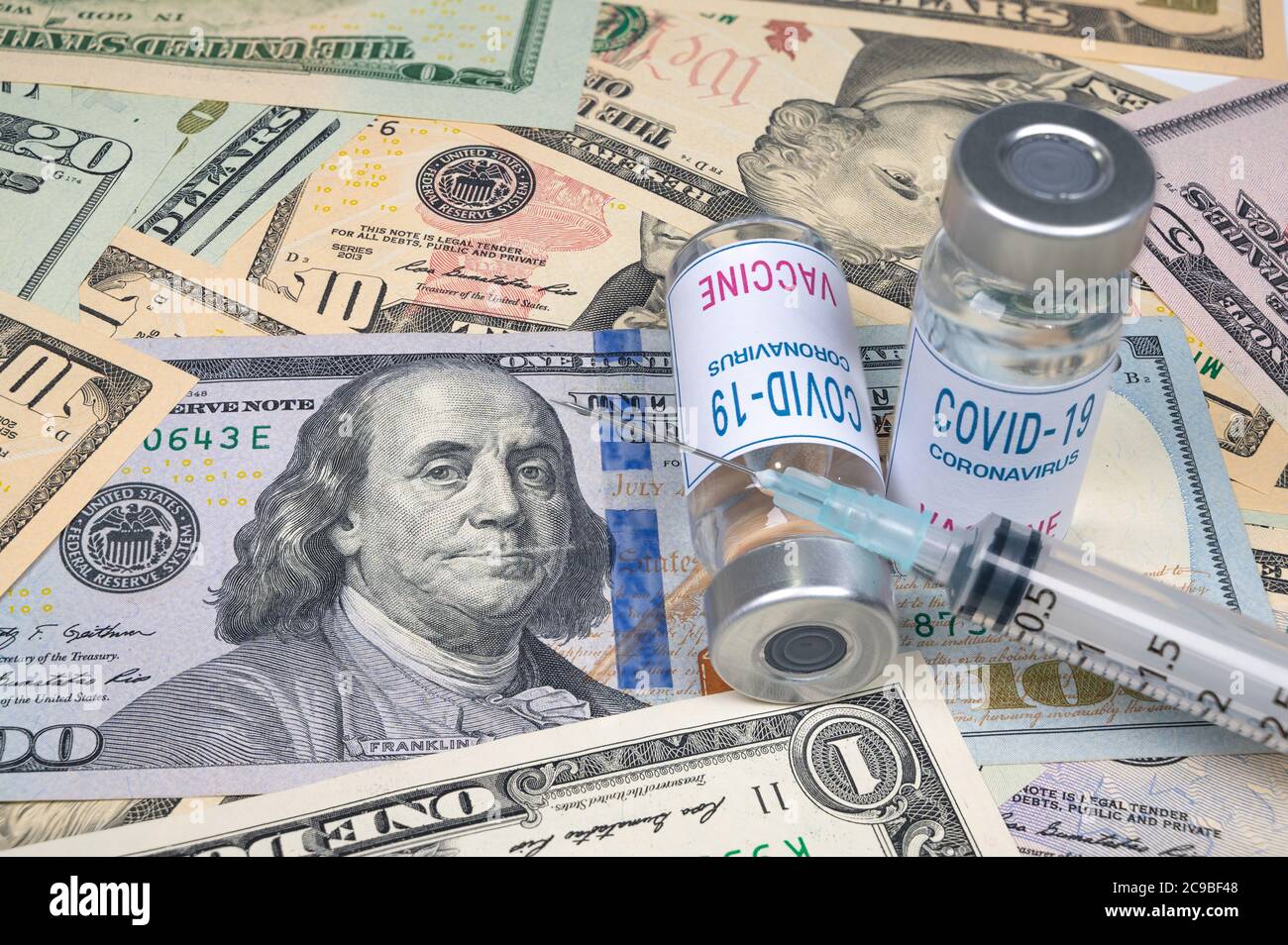 Spritzen und Covid-19-Impfampulle liegen auf dem US-Dollar. Stockfoto