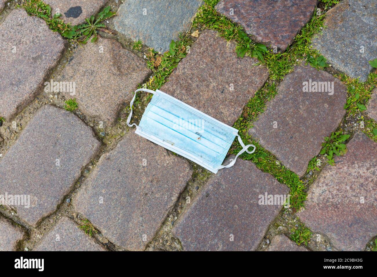 Lübeck, Schleswig-Holstein - 22. Juni 2020: Blaue Gesichtsmaske auf Kopfsteinpflaster. Verloren oder weggeworfen. Verschmutzung der Umwelt. Stockfoto