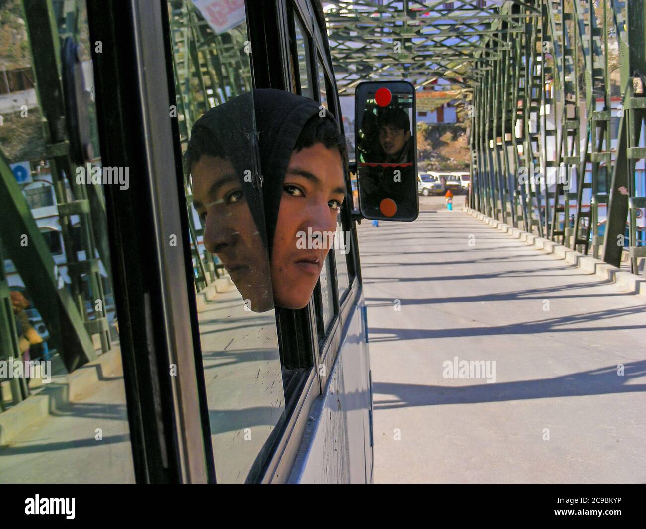Ein Tourist, der durch das Busfenster schaut und seine Reflexion auf dem Weg zum Badrinath Tempel Himalaya Bergkette mit dem Ganges, der durch ihn fließt. Stockfoto