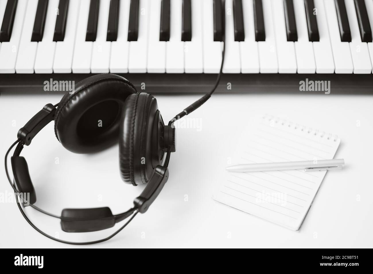 Musikvorlage mit Keyboard-Synthesizer mit Kopfhörer auf weißem Hintergrund. Stockfoto