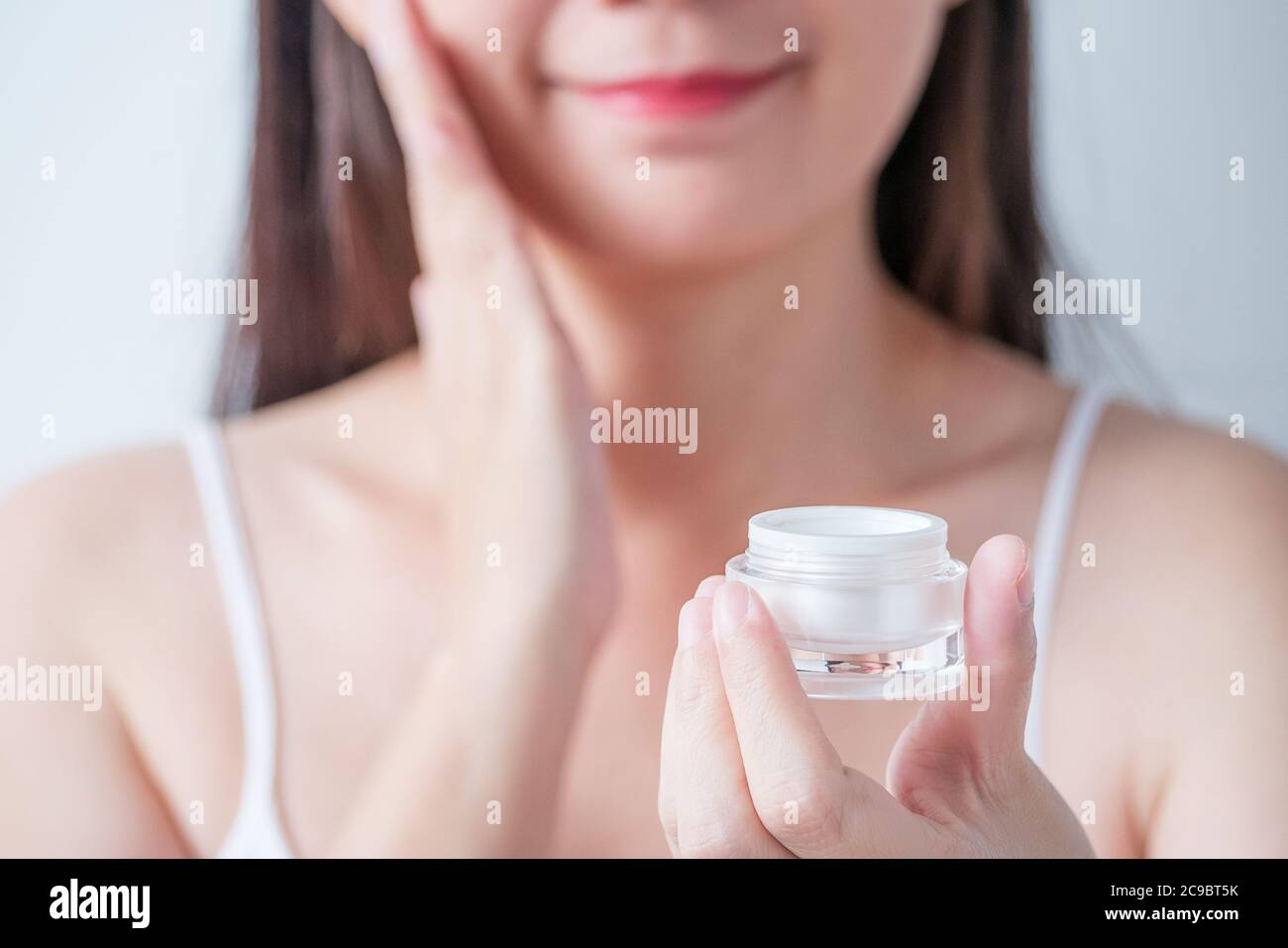 Kosmetik für Schönheit Hautpflege, Gesichtsbehandlung Konzept. Frau gelten Feuchtigkeitscreme Lotion auf ihr Gesicht aus Luxus weiße kosmetische Creme Verpackung Stockfoto