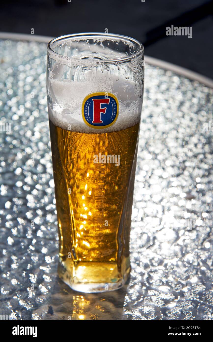 Ein halb leeres Glas Foster's lagedr auf einem Tisch Stockfoto
