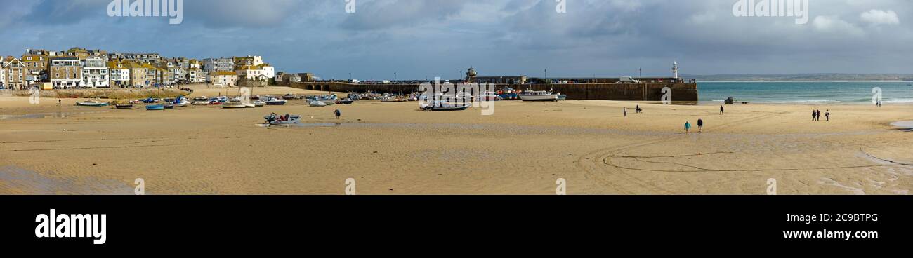 Panoramablick auf den sonnenbeschienenen Hafen von St. Ives und die Küstenstadt bei Ebbe im September mit bewölktem Himmel in der Ferne, Cornwall, England, Großbritannien Stockfoto