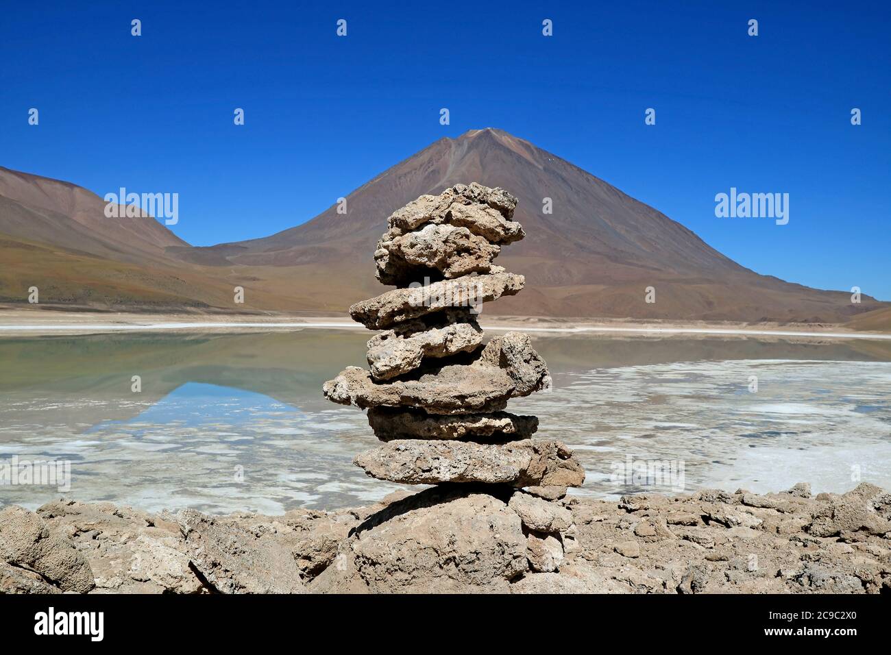 Steinstapel von Reisenden an der Küste der Laguna Verde oder dem Grünen See mit Vulkan Lincancabur im Hintergrund, Bolivien Stockfoto