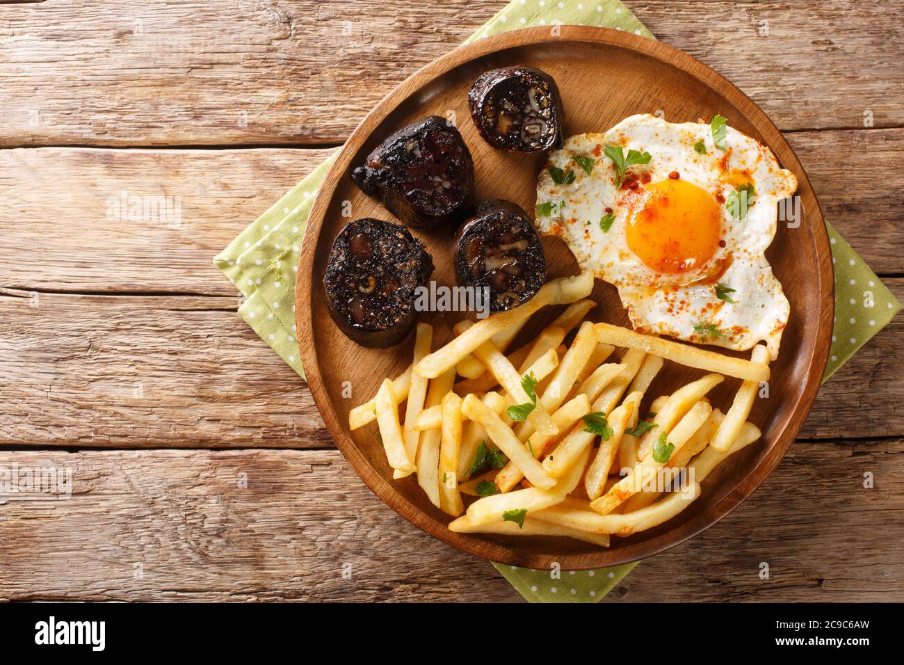 Huevos Rotos mit Bratkartoffeln und Blutwurst in der Nähe auf einem Teller auf dem Tisch. Horizontale Draufsicht von oben Stockfoto