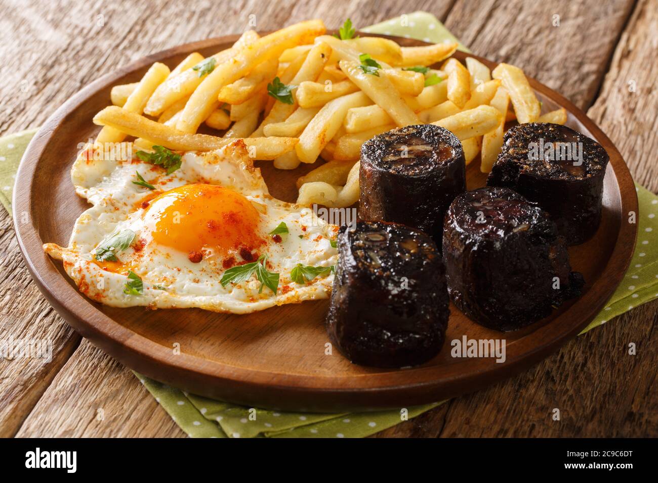 Huevos Rotos mit Bratkartoffeln und Blutwurst in der Nähe auf einem Teller auf dem Tisch. Horizontal Stockfoto