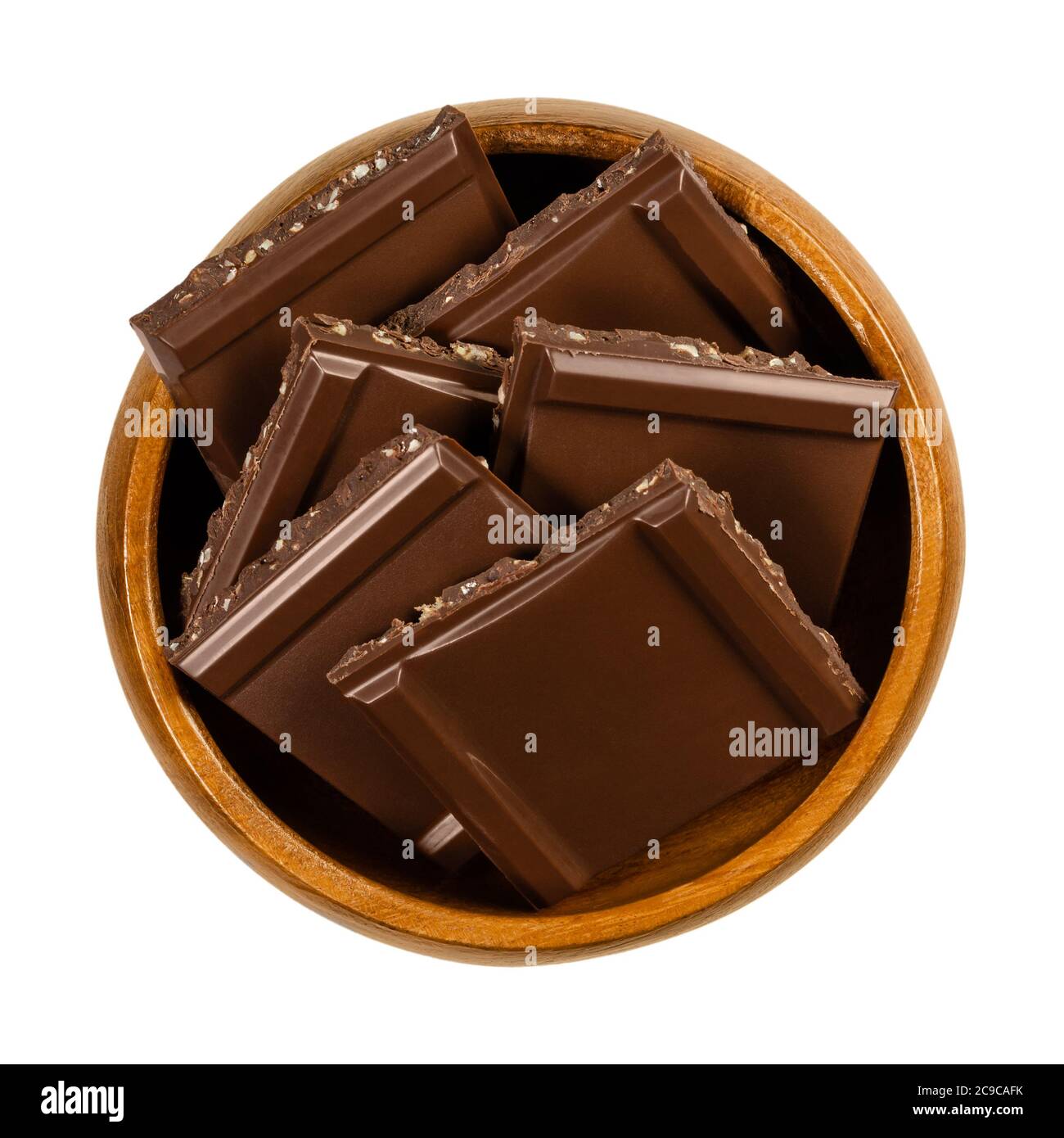 Dunkle Nussschokolade, in quadratische Stücke geschnitten, in einer Holzschale. Schwarze Schokolade mit feinen Nußstückchen, verzehrfertig als süß und leicht bitter Stockfoto