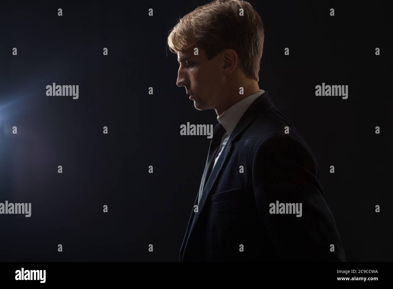 Bewusstsein und strategisches Denken bei der Arbeit. Junger Geschäftsmann, durchdachtes Porträt im Profil, schwarzer Hintergrund. Stockfoto