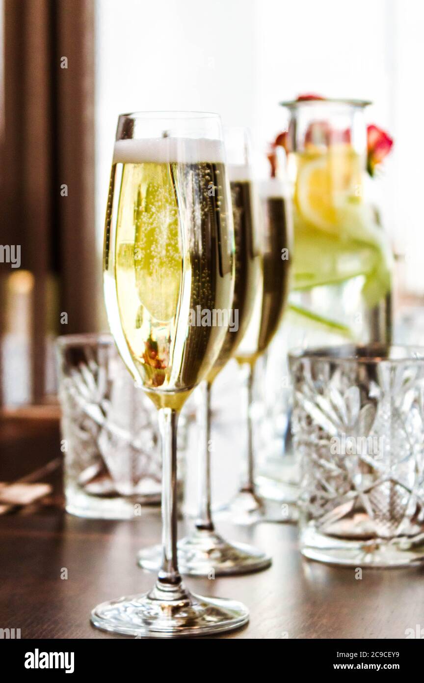 Gedeckten Tisch mit drei Gläsern Champagner und Karaffe und Glas Limonade auf Bokeh Hintergrund. Stockfoto