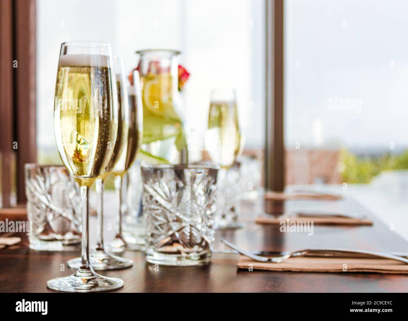 Gedeckten Tisch mit vier Gläsern Champagner und Karaffe und Glas Limonade auf Bokeh Hintergrund. Stockfoto