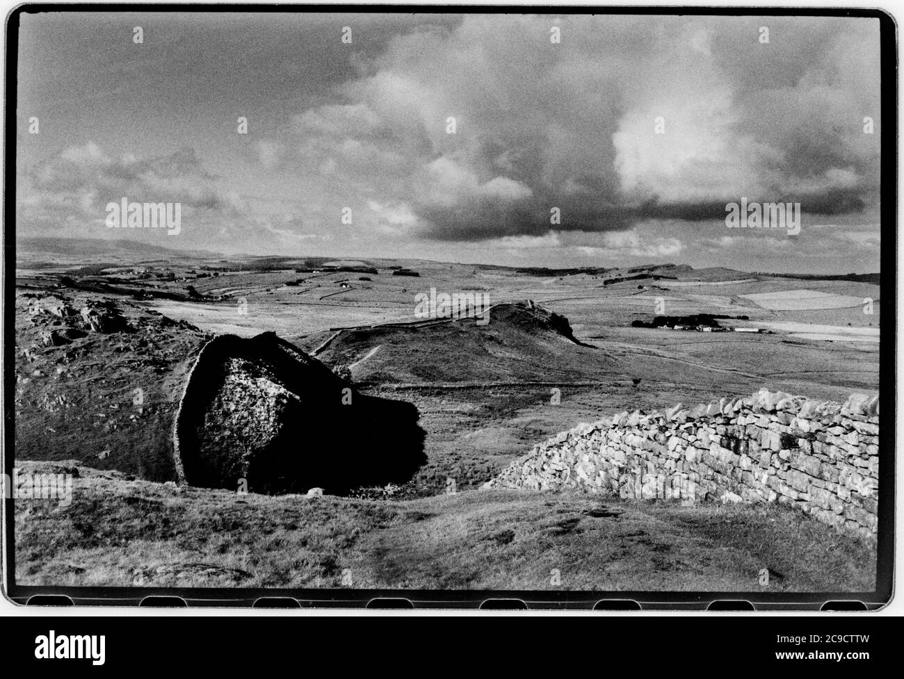 Hadrian Wall Northumberland England UK 1990 Hadrian's Wall (Latein: , Vallum Aelium), auch bekannt als die römische Mauer, Picts' Wall, Oder Vallum Hadriani in Latein, ist eine ehemalige defensive Befestigung der römischen Provinz Britannia, begonnen in AD 122 in der Regierungszeit des Kaisers Hadrian.[3] Es lief von den Ufern des Flusses Tyne in der Nähe der Nordsee zum Solway Firth auf der Irischen See, Und war die nördliche Grenze des Römischen Reiches, unmittelbar nördlich davon waren die Länder der nördlichen Alten Briten, einschließlich der Picts. Es hatte einen Steinsockel und eine Steinmauer. Es gab Milecastles mit zwei Stockfoto