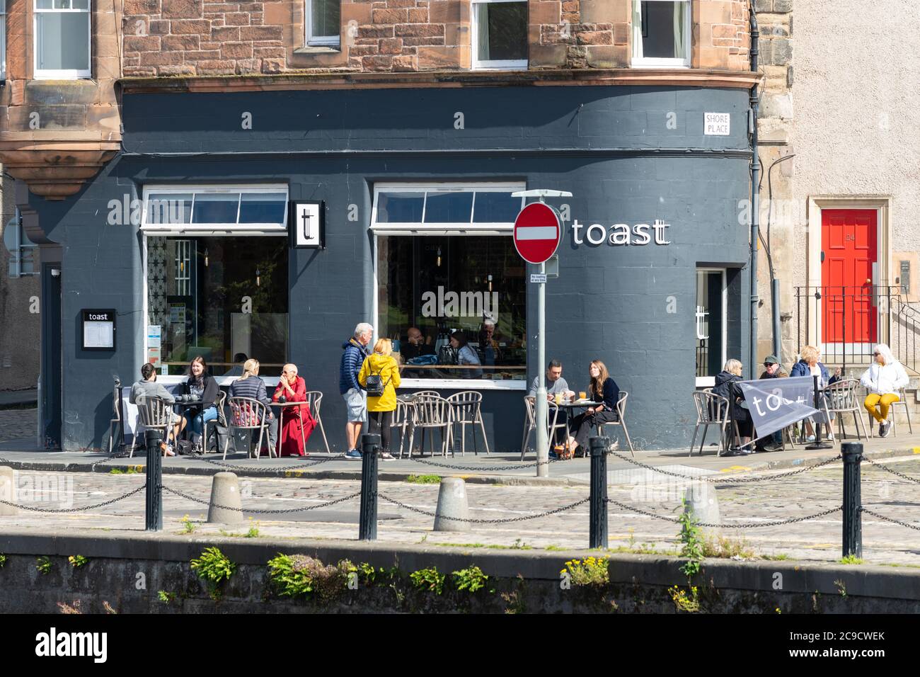 The Shore of Leith - Toast Weincafé - Menschen sitzen an Pflaster-Tischen in der Sonne, Leith, Edinburgh, Schottland, Großbritannien Stockfoto
