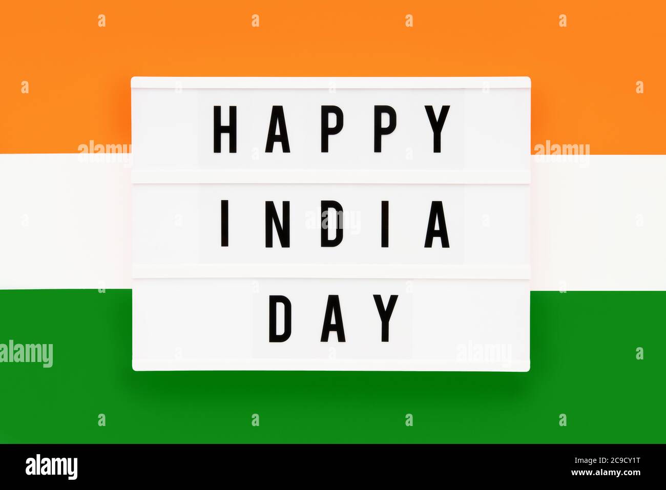 HAPPY INDIA DAY in einem Leuchtkasten auf einem Hintergrund der indischen Flagge Farbe geschrieben. Datum des Unabhängigkeitstages. Draufsicht. Stockfoto