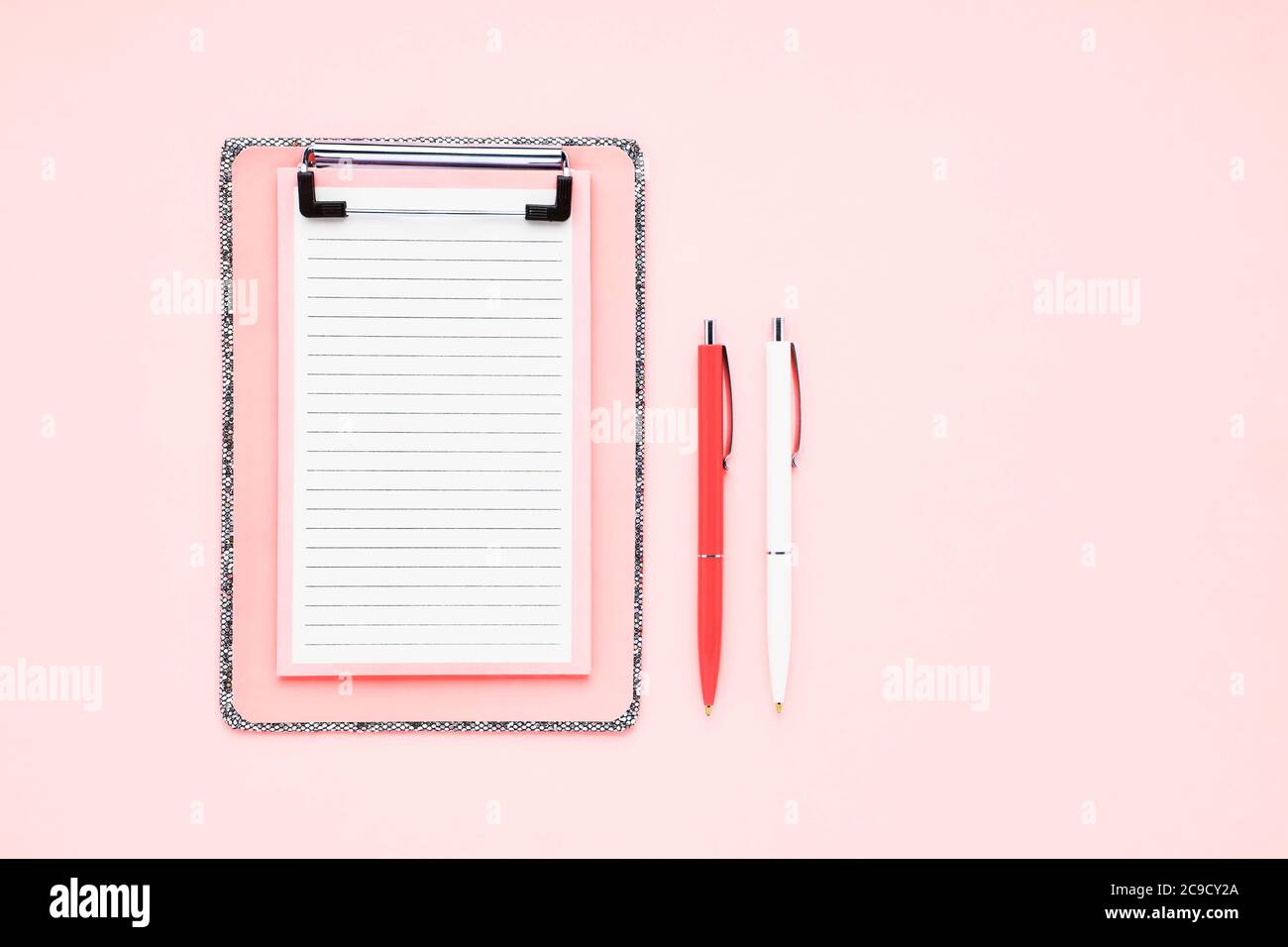 Leerer Clipboard Mockup und Kugelschreiber auf rosa Hintergrund. Draufsicht, Kopierbereich für Text. Zurück zur Schule, Deadline, Morgenkonzept. Stockfoto