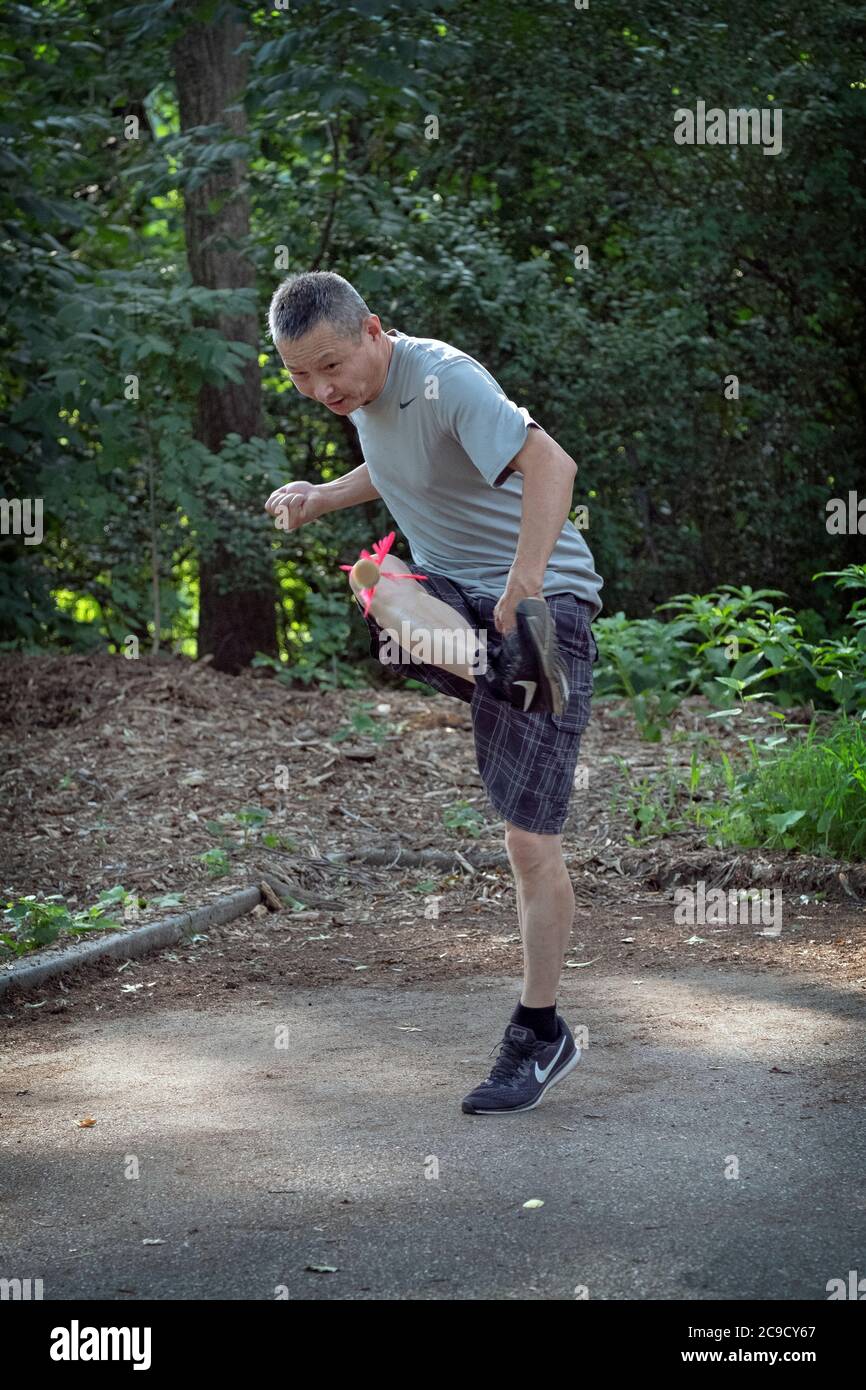 Ein Mann spielt Jianzi, eine traditionelle chinesische Sportart, bei der die Spieler versuchen, einen schwer gewichteten Federball in der Luft zu halten, indem sie ihren Körper benutzen. Stockfoto