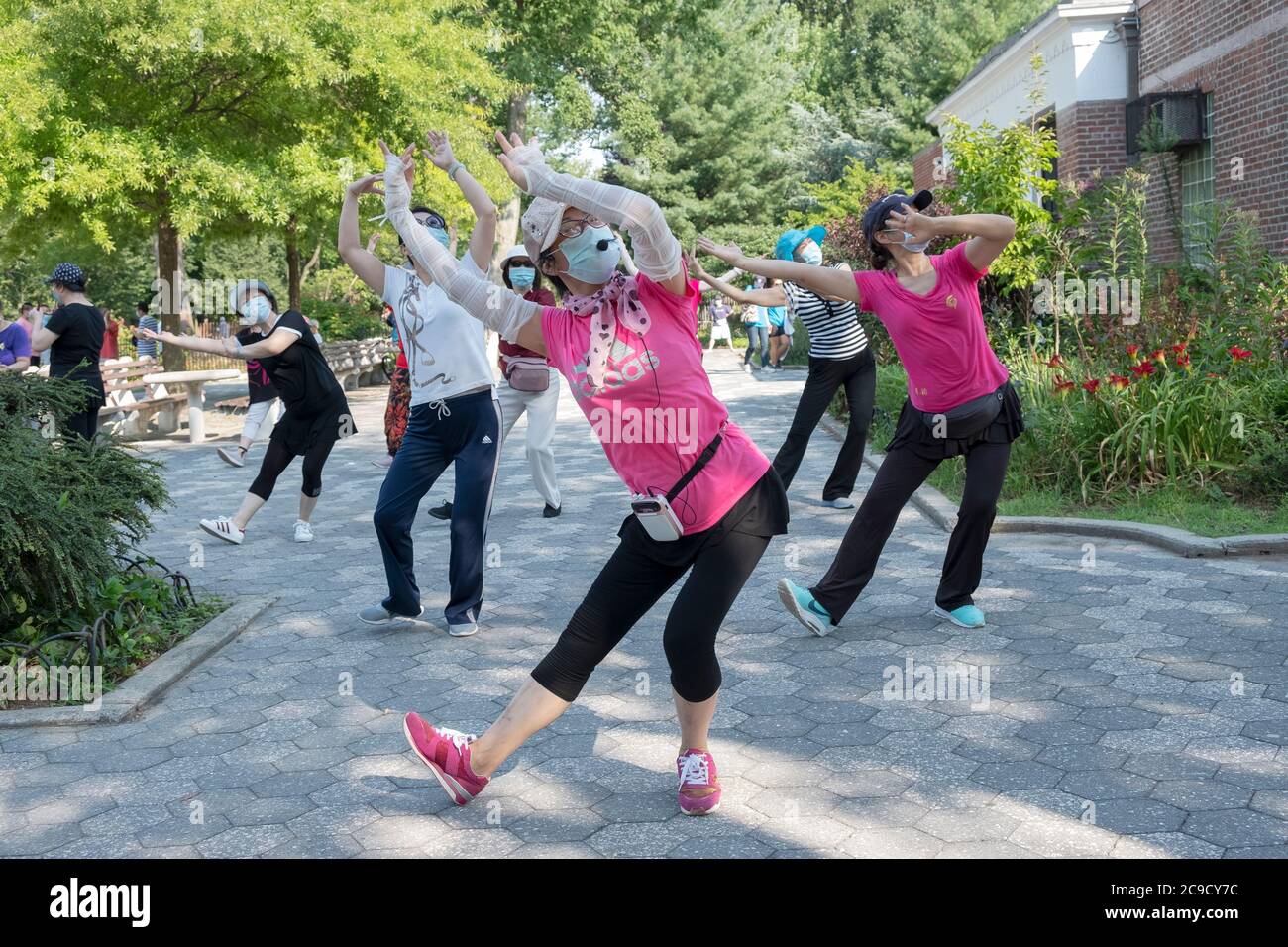 Eine Gruppe von chinesisch-amerikanischen Frauen, die Masken tragen und Distanzen beobachten, üben modernen chinesischen Tanz. Bei einem Outdoor-Kurs in Flushing, Queens, NYC Stockfoto