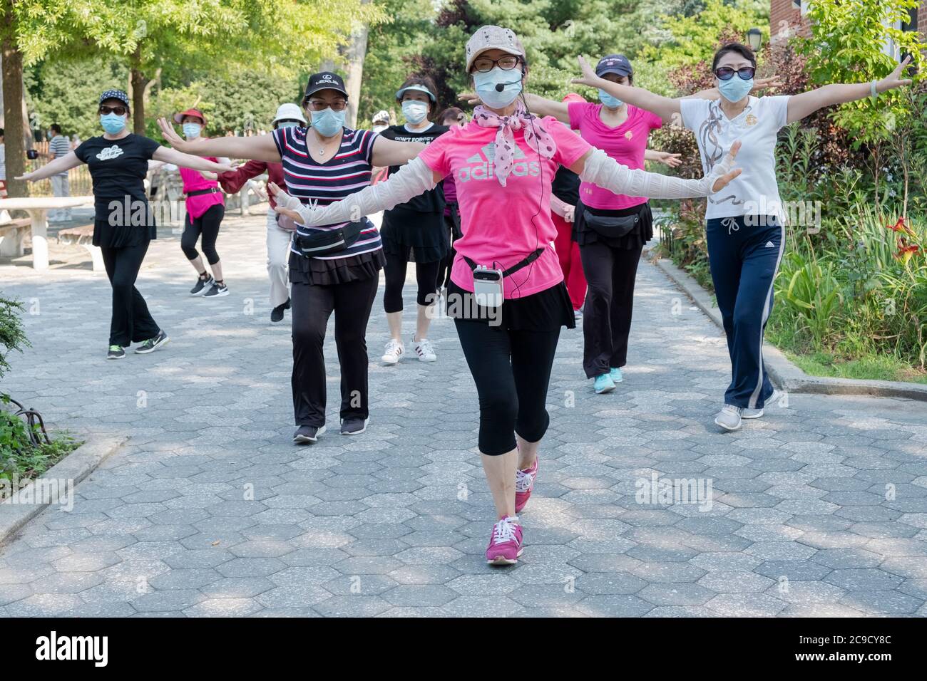 Eine Gruppe von chinesisch-amerikanischen Frauen, die Masken tragen und Distanzen beobachten, üben modernen chinesischen Tanz. Bei einem Outdoor-Kurs in Flushing, Queens, NYC Stockfoto
