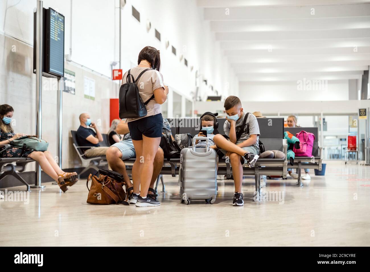 Sevilla, Spanien - 4. Juli 2020: Maskierte Familie wartet auf die Abfahrt am Flughafen Stockfoto
