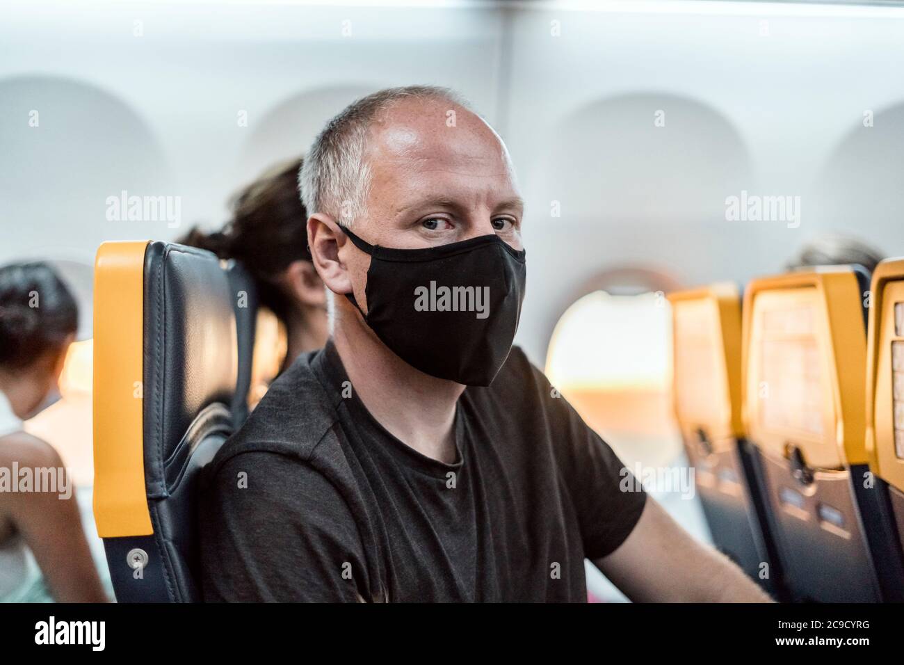 Mann mit Schutzmaske sitzt im Flugzeug Stockfoto