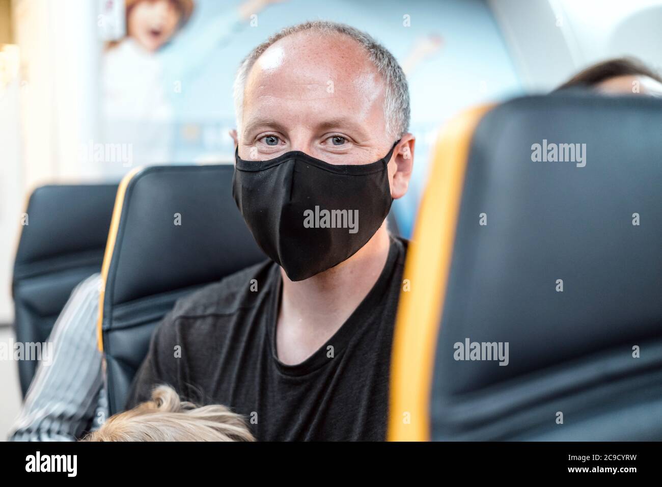 Mann mit Schutzmaske sitzt im Flugzeug Stockfoto