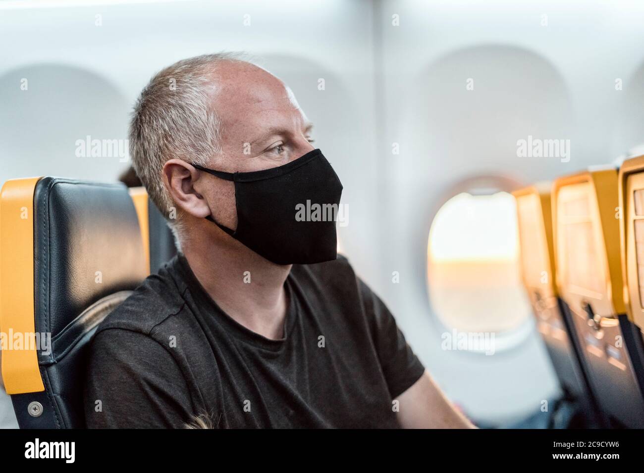 Mann mit Schutzmaske sitzt im Flugzeug Stockfoto