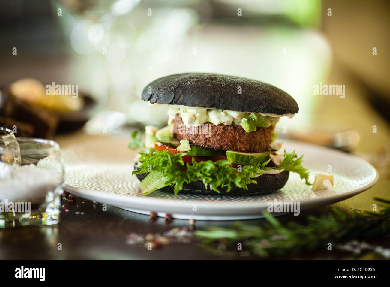 Veganer Burger. Schwarzes Brötchen, TofuAvocadoSalat, Mayonnaise, Gurke, Tomate, frischer