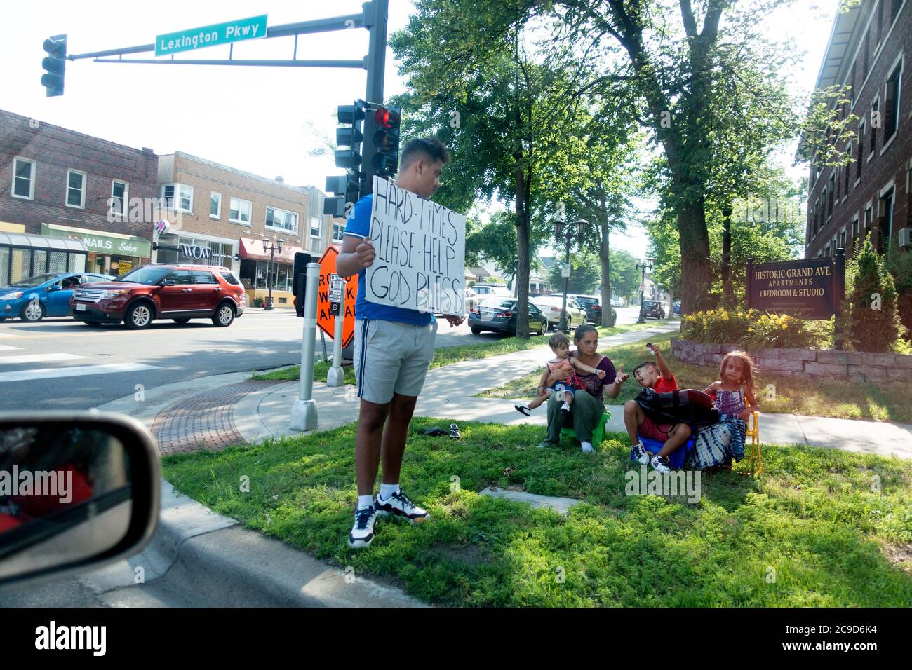 Familie draußen an der Straßenecke mit einem Mann mit einem großen Schild, der um Geld bettelte. St. Paul Minnesota, USA Stockfoto