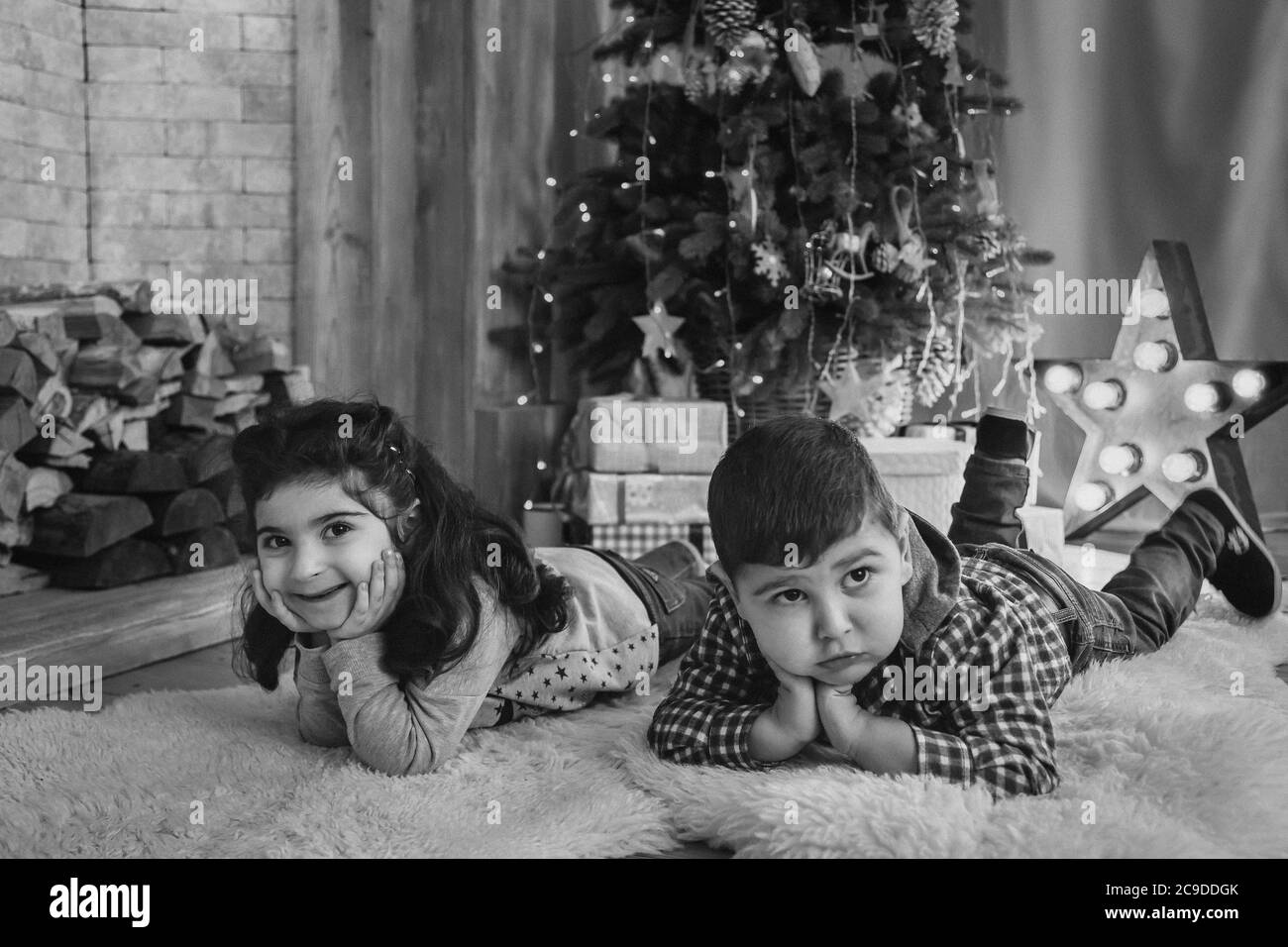 Weihnachtsporträt von schönen lächelnden kleinen Kindern liegen auf dem Boden mit Geschenken unter dem weihnachtsbaum. Winterurlaub Weihnachten und Neujahr Konzept Stockfoto