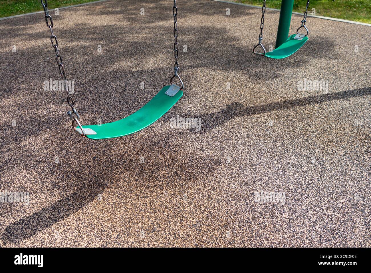 Eine Reihe von Schlingen schwingt auf einem Kinderparkplatz mit weichem gummiartigen Boden Stockfoto