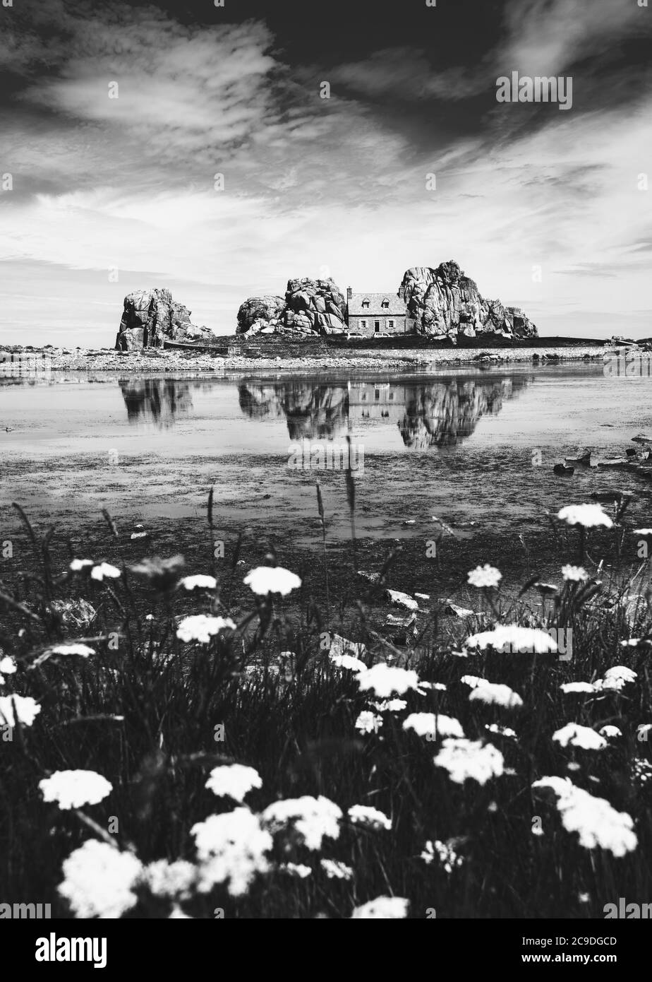 Castel MEUR oder La Maison du Gouffre oder Haus zwischen Felsen an der Pink Granite Coast, Plougrescant, Frankreich. Reflexion im Wasser. Schwarzweißfoto Stockfoto