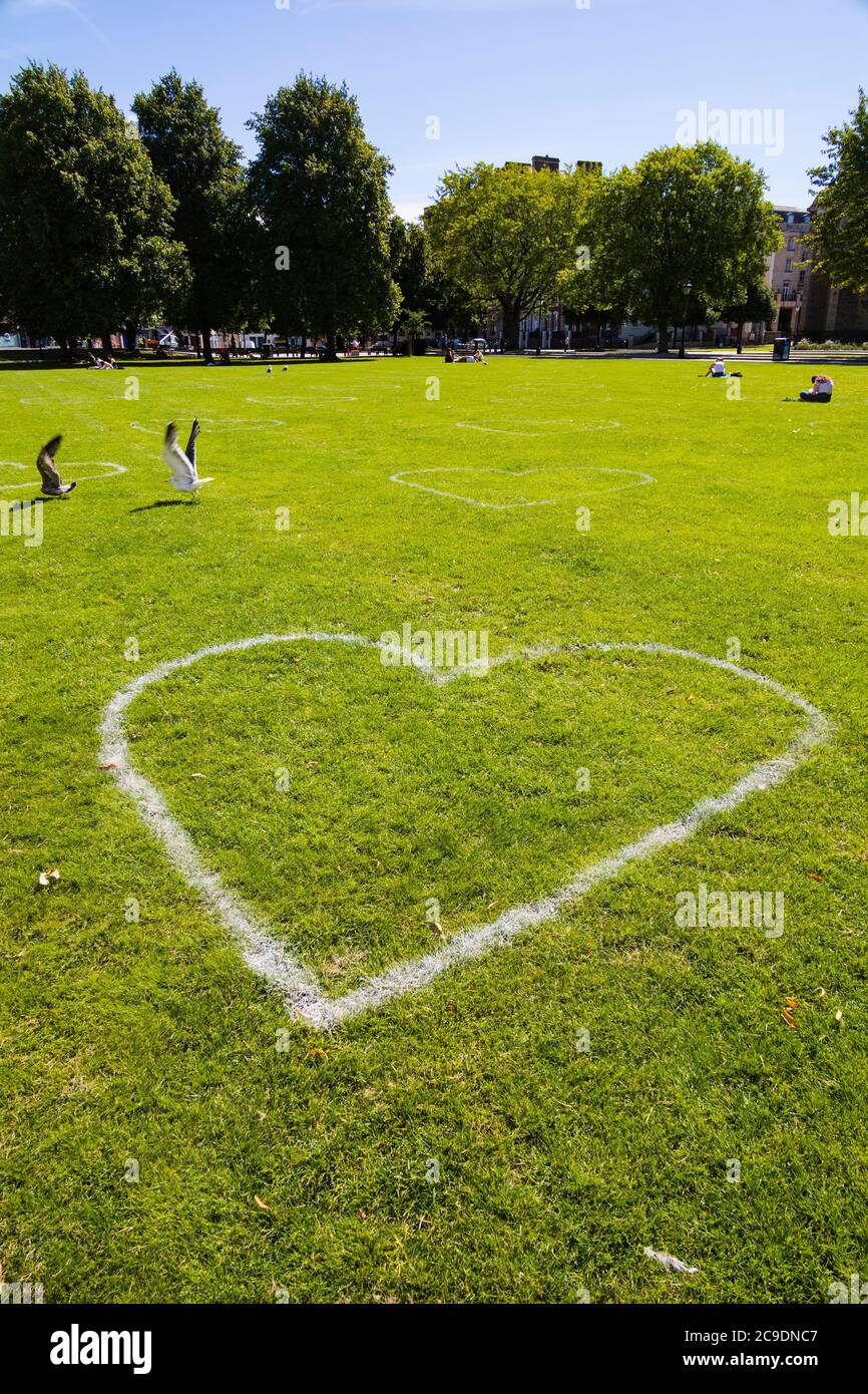 Lovehearts auf das Gras gemalt, um einen sicheren 2 Meter Sicherheitsabstand bei College Green anzuzeigen, während der Covid 19 Pandemie. Bristol, England. Juli 2020 Stockfoto