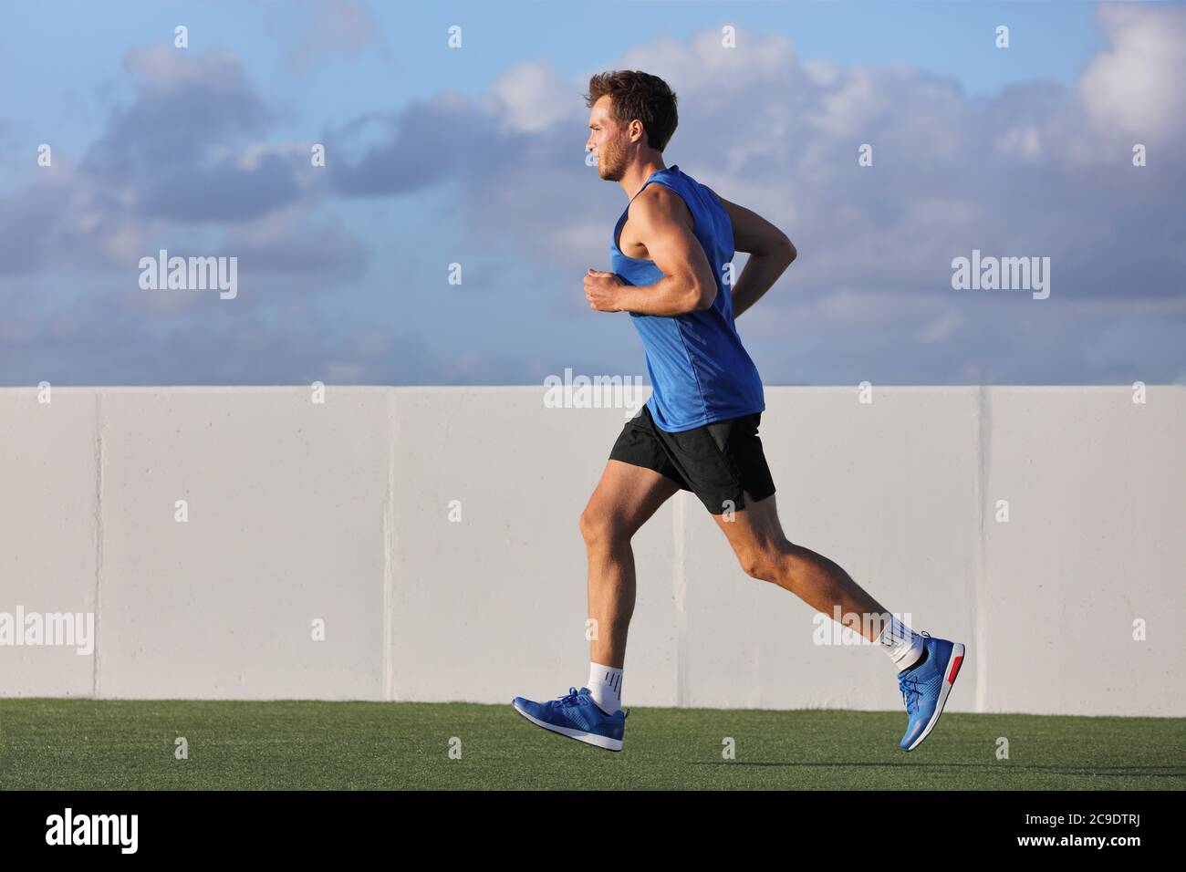 Junger Mann Läufer läuft im Stadtpark auf Sommerrasen im Freien bei Sonnenuntergang im Outdoor Stadion Fitness Center. Gesunder Lebensstil. Stockfoto