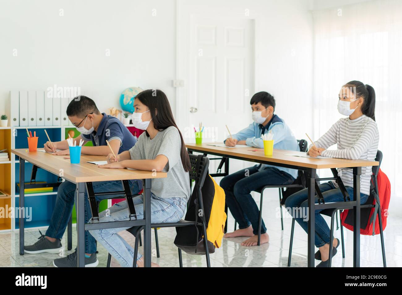 Gruppe von asiatischen Grundschüler tragen hygienische Maske, um den Ausbruch von Covid 19 im Klassenzimmer zu verhindern, während wieder in der Schule öffnen ihre sch Stockfoto