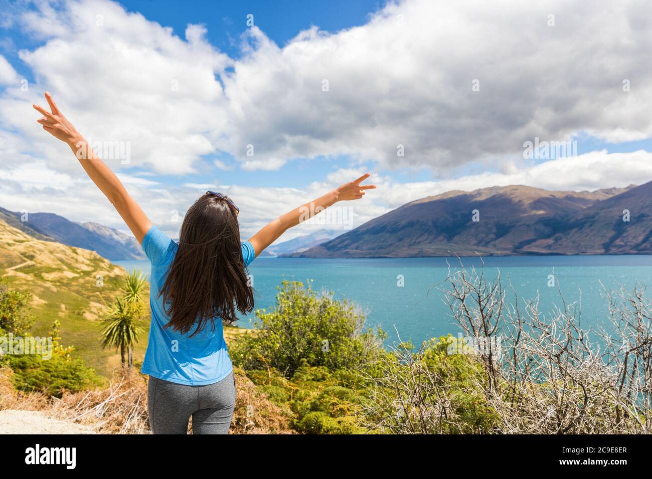 Neuseeland reisen glückliche touristische Frau mit den Armen auf Wanaka See Natur Landschaft im Freien. Wanderlust Abenteuer junges Mädchen mit Frieden Hand Zeichen. Stockfoto